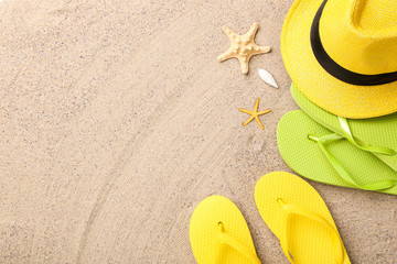Fototapeta na wymiar Pairs of flip flops with starfish and hat on beach sand