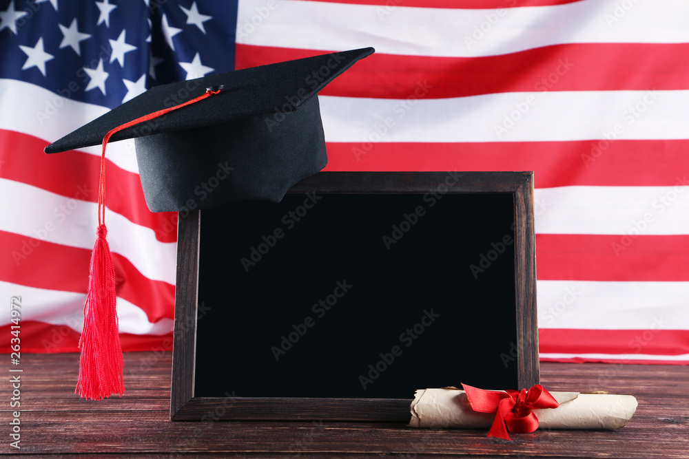 Wall mural Graduation cap with diploma and blank frame on brown wooden table