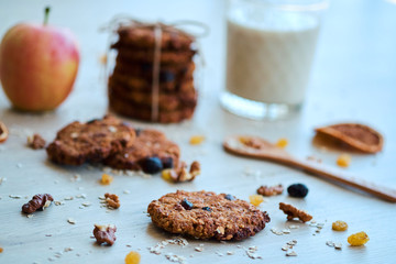 Homemade oatmeal cookies with walnut, raisins and milk on a wooden table