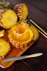Splash fresh fruit juice with exotic pineapple on a wooden brown table. A composition made of ananas. Top wiev. 