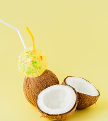 Fresh Coconut cocktail with a straws on yellow background, copy space