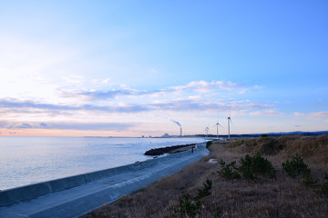 海岸線に火力発電所と風力発電所が見える丘