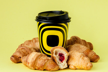 Paper cup of coffee and croissants on a yellow background, Copy space