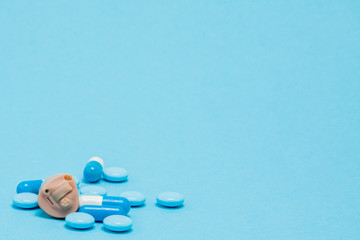 Hearing aid and blue pills on blue background. Medical, pharmacy and healthcare concept. Copy...