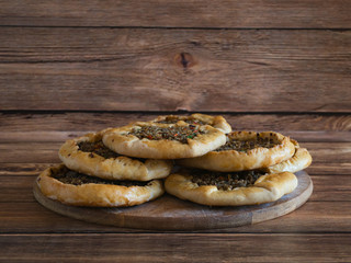 Arabic meat sfiha over a wooden table.
