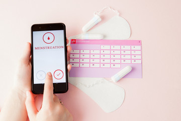 Tampon, feminine, sanitary pads for critical days, feminine calendar, pain pills during menstruation on a pink background. Tracking the menstrual cycle and ovulation