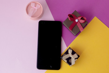 Phone screen and gifts on colored background. Minimal concept. Flat lay. top view.Online promotions and discounts. Holiday gifts and surprises. Present. Valentine's Day. Internet technologies