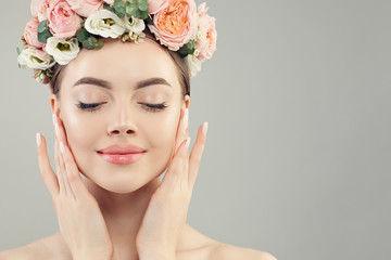 Beautiful woman face closeup. Healthy spa model with clear skin, manicured nails and flowers