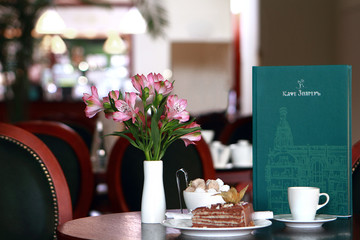 cups of coffee and a piece of cake on a plate on the background of the city