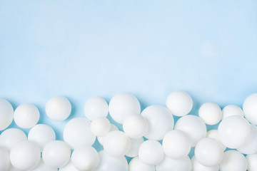 Pastel blue table with white balloons border top view. Party or birthday background. Flat lay style.