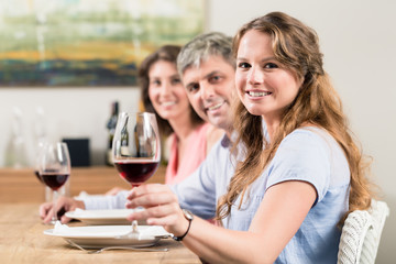Woman holding wine glass sitting with family