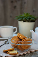 Ginger cookies with cream, biscuit for tea of coffee, on wooden table. Sweet healthy food snack with coffee, tea cup.