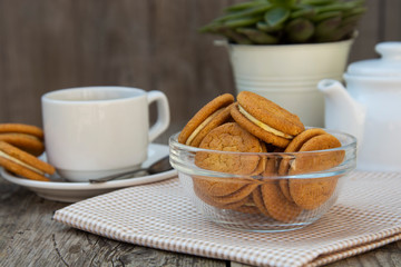 Obraz na płótnie Canvas Ginger cookies with cream, biscuit for tea of coffee, on wooden table. Sweet healthy food snack with coffee, tea cup.