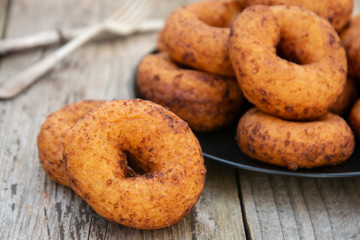 Naklejka na ściany i meble Homemade donuts. round, circle delicious donuts in black plate, wooden background. Isolated dessert or breakfast.