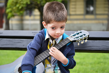 child boy with a guitar in a park