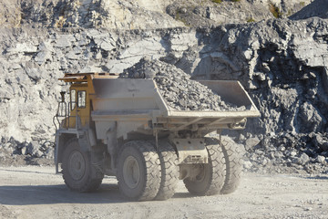Large mining truck loaded with rock ore in a limestone quarry.