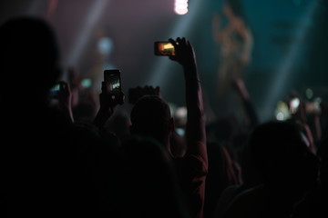 Hand of a fan with a phone filming a concert