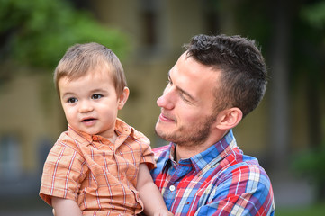 father holds son in a park