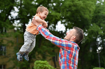 father holds son in a park
