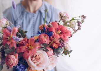 Young woman in a light blue dress holding a bouquet of flowers. Romantic concept.