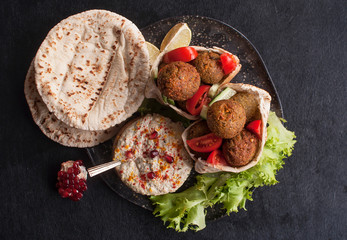 Traditional homemade hummus, falafel in pita and tahini with fresh tomato salad and spices on a...