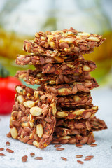 Homemade vegetarian (vegan) cracker flax seed and sunflower with tomato. Healthy gourmet snack. Proper nutrition, diet, superfood. Selective focus