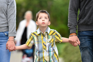 mother, father and son holding hands in park
