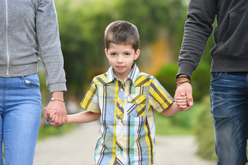 mother, father and son holding hands in park