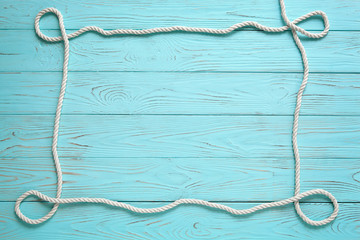 Frame made of white rope on a wooden blue background.