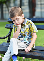 sad child boy sitting on a bench