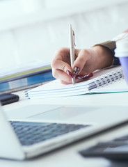 Businesswoman making notes with silver pen in office background. Just hands over the table. Business finance savings loan and credit concept.