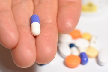 Various medical pills and capsules picked up with hand