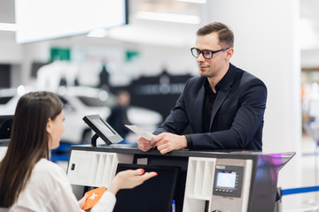 Handsome businessman handing over air ticket at airline check in counter