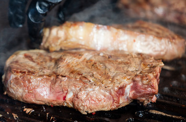 Beef steak cooking. Rib eye steak. Raw meat. Juicy marbled meat on BBQ grill. Medium rare meat roasting