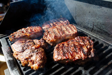 Beef steak cooking. Rib eye steak. Raw meat. Juicy marbled meat on BBQ grill. Medium rare meat roasting