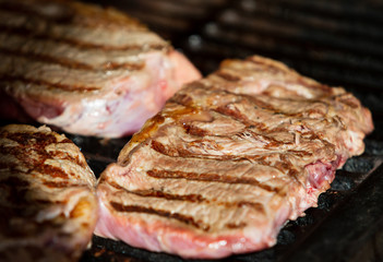 Beef steak cooking. Rib eye steak. Raw meat. Juicy marbled meat on BBQ grill. Medium rare meat roasting
