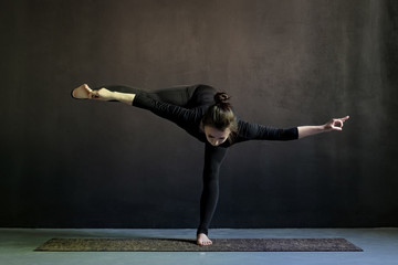 Caucasain girl standing in yoga asana, vbalance on foot.