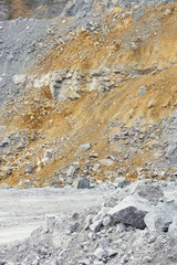 Scree of stone ore in a quarry with impurities of a clay soil of yellow color, closeup.