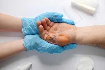 Doctors hands holding male hand with bloody gash on big finger. Doctor examining of the patient. Patient cheering and support. Wound treatment with antiseptic.