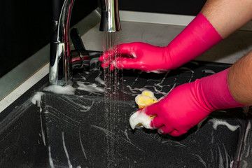 The process of washing the dark sink, hands close-up. A man in pink gloves washes a sink. Cleaning, clean up.