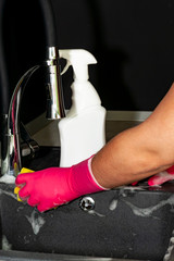 The process of washing the sink, hands closeup. Putting detergent on the dish sponge. Cleaning.