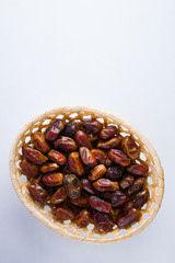 Dried dates on white background. Holy month of Ramadan, concept. Righteous Muslim lifestyle. Starvation. Dates in wooden basket. Vegetarian food. Copy space