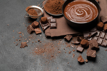 ceramic bowl of chocolate cream or melted chocolate and pieces of chocolate isolated on dark concrete background