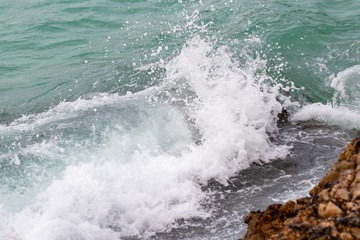 The ocean waves hit the rocks on the rocky beach in the morning, Ocean waves hit the rocks at the beach.