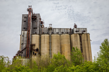 Large abandoned factory with tall silos and rusty sides in the deep south