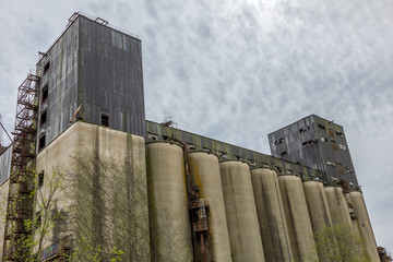 Looking up at a large abandoned factory with huge silos in the deep south