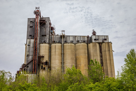 Large abandoned factory with tall silos and rusty sides in the deep south
