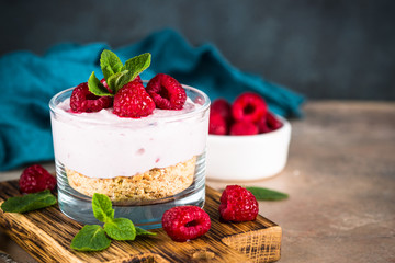 No baked cheesecake with raspberry in glass jar.