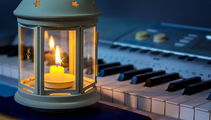 Lantern with a candle near the piano in the evening. Evening concert with candles_