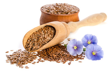 Flax seeds in the wooden scoop and  beauty flowers isolated on white background.